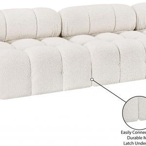 K&ouml;nnte beinhalten: Cremefarbenes modulares Sofa mit Boucl&eacute;-Stoffstruktur. Das Sofa hat ein abgerundetes Design und besteht aus mehreren Abschnitten, die auf verschiedene Weise konfiguriert werden k&ouml;nnen. Langlebige Metallverschl&uuml;sse darunter verbinden die Abschnitte leicht.