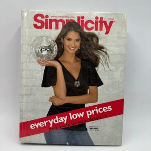 May include: Simplicity Holiday catalog cover featuring a woman holding a disco ball. The cover has the text "Simplicity" in red, and "everyday low prices" in a red banner. The woman is wearing a black top and jeans.