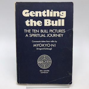 May include: A dark blue book with the title "Gentling the Bull" in white lettering. The book also features the text "The Ten Bull Pictures A Spiritual Journey" and the author's name, Myokyo-Ni. The Zen Centre London logo is visible.