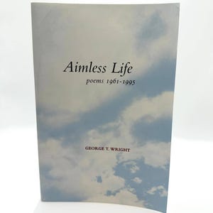 Puede incluir: Un libro de bolsillo titulado "Aimless Life" con una portada con temática de cielo. La portada presenta un fondo azul claro con nubes blancas. El título y el nombre del autor, George T. Wright, están impresos en negro.