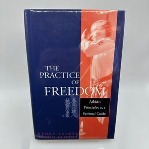 May include: A hardcover book titled "The Practice of Freedom" with a blue cover and a red and white image of a person practicing Aikido. The book also includes the text "Aikido Principles as a Spiritual Guide" and the author's name, Wendy Palmer.