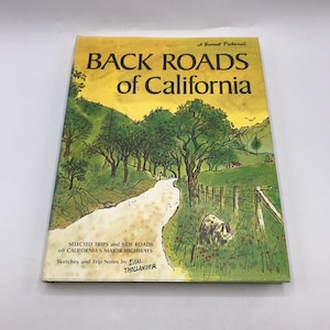 Puede incluir: Un libro antiguo titulado "Back Roads of California" con una ilustración escénica de una carretera que serpentea por un paisaje. La portada es amarilla y verde, con texto e ilustraciones. El libro es un Sunset Pictorial.