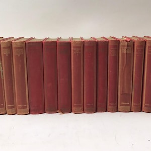 May include: A long row of twenty-two matching hardcover books with solid red cloth covers and gold lettering on the spines. The books are arranged vertically side-by-side, displaying uniform height and thickness, creating a continuous red line.