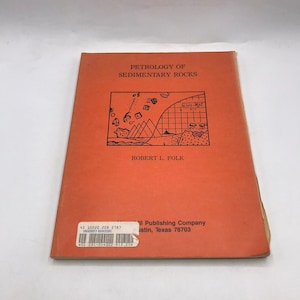 May include: A softcover book titled Petrology of Sedimentary Rocks by Robert L. Folk with a solid orange cover. The front features a black line drawing of geological formations, a grid, and mathematical formulas. A white bookstore sticker is present.