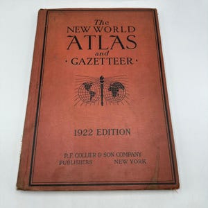 Puede incluir: Un atlas antiguo de 1922, titulado "The New World Atlas and Gazetteer". La portada es de color marrón rojizo con texto negro y un diseño de globo. Publicado por P.F. Collier & Son Company, Nueva York.