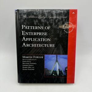 Può includere: Un libro con copertina rigida intitolato "Patterns of Enterprise Application Architecture" di Martin Fowler. Il libro ha una copertina nera con testo bianco e un dorso rosso. La copertina presenta un'illustrazione di un ponte.
