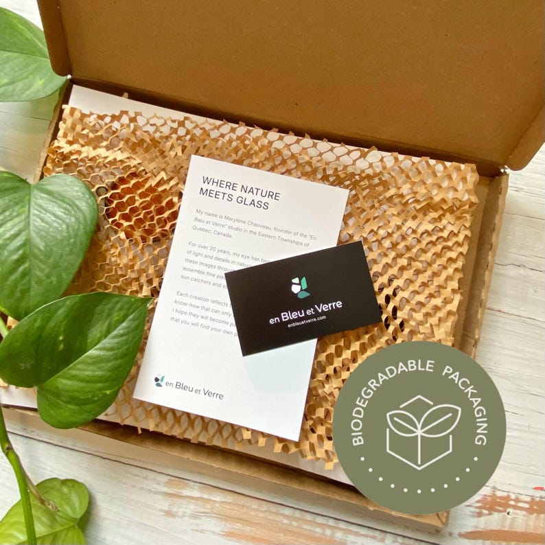 May include: A brown cardboard shipping box containing tan honeycomb paper filler, a white informational card with the text WHERE NATURE MEETS GLASS, and a small black business card with the white text en Bleu et Verre and a logo.