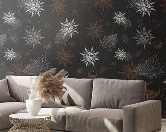 May include: A dark grey wall featuring a celestial pattern of suns, moons, and stars in white and bronze. A grey sofa, white pillow, and gold side table with a white vase are positioned in front of the wall.