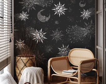 May include: A room with black wallpaper patterned with suns, moons, and stars. A light brown rattan chair with a book is in front of the wallpaper. A woven basket, a small tote bag, and a blanket are in the foreground.