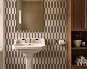 May include: A bathroom scene featuring a white pedestal sink with gold fixtures, a rectangular mirror, and a wooden cabinet. The wall has a repeating pattern of vertical rectangles in shades of brown and beige. A roll of toilet paper is mounted on the wall.
