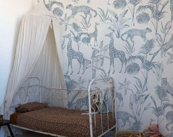 May include: A white metal bed frame with a canopy, a patterned comforter, and a woven basket. The wallpaper features a blue and white jungle scene with giraffes, leopards, and tropical plants. A small round rug is on the floor.