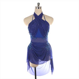 May include: A royal blue dance dress featuring a crisscross halter neckline, a sheer midriff panel, and a layered skirt. The bodice is embellished with scattered clear crystals and dense blue beadwork at the waist and sides.
