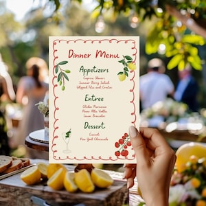 Può includere: Un menu per la cena color crema con un bordo rosso, tenuto in mano. Il menu comprende antipasti, piatti principali e dessert. Limoni e cibo sono in primo piano. Lo sfondo è sfocato.