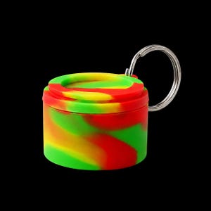 May include: A small, cylindrical silicone container featuring a vibrant, swirled pattern of bright red, yellow, and green colours. The container has a matching lid and is attached to a circular silver metal split ring for easy attachment to keys.