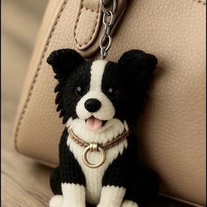May include: A black and white dog keyring with a happy expression. The dog has a white stripe down its face and a brown collar with a gold ring. The keyring is attached to a silver chain.