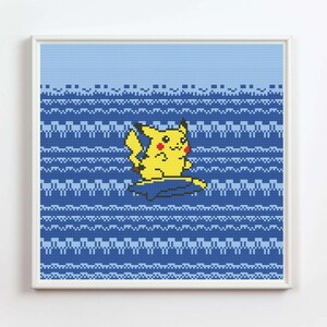 May include: A framed cross-stitch featuring Pikachu, a yellow creature with red cheeks, on a blue background. The background has a pattern of horizontal blue lines. The artwork is in a white frame.