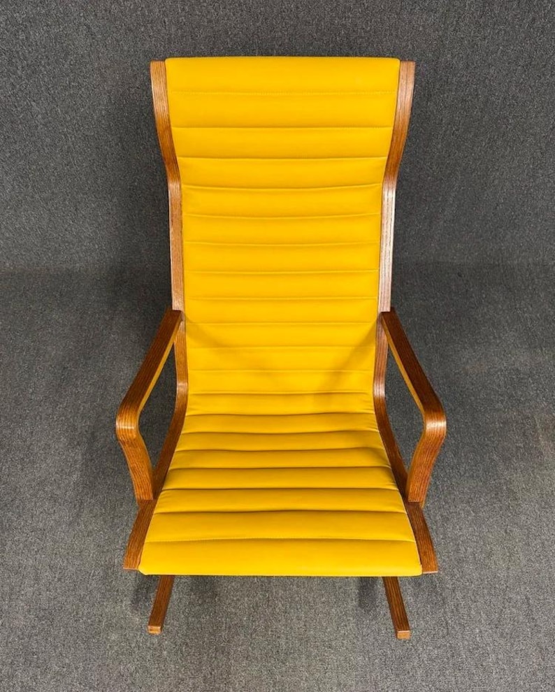 May include: A high-backed, mid-century modern armchair with a bright yellow, horizontally ribbed seat and back. The frame and armrests are made of wood with a warm, natural finish. The chair has a minimalist design.