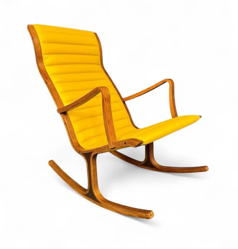 May include: A mid-century modern rocking chair with a bright yellow, padded seat and backrest. The chair has a wooden frame with curved armrests and rockers. The chair's design is simple and elegant, with a focus on comfort and style.