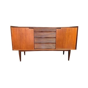 May include: A mid-century modern wooden sideboard with a warm, reddish-brown finish. The cabinet features two doors and three drawers with horizontal grooves. The sideboard is supported by four angled legs.