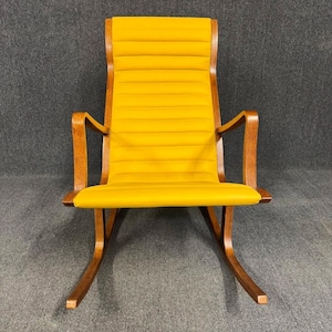 May include: A mid-century modern rocking chair with a bright yellow seat and backrest. The chair features a wooden frame with curved armrests and rockers. The seat and back are upholstered with horizontal stitched panels.