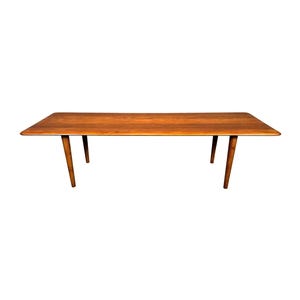 May include: A rectangular wooden table with a warm brown finish. The table has four tapered legs and a smooth, flat surface. The table is approximately 60 inches long and 30 inches wide.