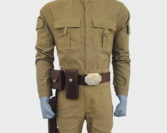 May include: A tan long-sleeved jumpsuit featuring a high collar, two chest pockets with flaps, and two thigh pockets. A dark brown leather belt with a large metallic buckle, two small pouches, and a holster attachment is worn around the waist.