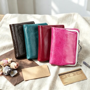 May include: Four rectangular wallets with a crinkled texture and a metal frame closure. The wallets are arranged in a row, featuring dark brown, teal, deep red, and bright pink colors. Each wallet has a smooth, shiny finish and a metallic clasp.