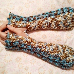 May include: A pair of fingerless gloves in a brown, white, and blue color scheme. The gloves are crocheted and have a textured pattern.