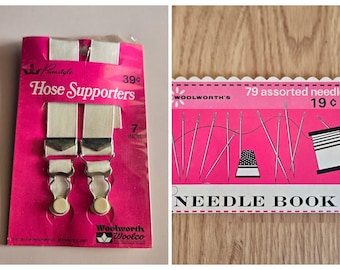 May include: Two vintage items: a pink card with "Primstyle Hose Supporters" with white straps and metal clasps, 7 inches (17.78 cm) long. Next to it is a "Woolworth's" needle book with 79 assorted needles.
