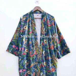 May include: A blue velvet kimono robe featuring a vibrant floral and botanical print in shades of red, green, and yellow. The garment has an open front, wide sleeves, and a white and blue striped lining. The text MaharajaCraftArt is visible.