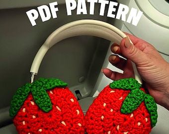 Pode incluir: Fones de ouvido com protetores de ouvido de morango vermelho de crochê e uma faixa de cabeça branca. Os protetores de morango têm folhas verdes e sementes brancas. O texto "PDF PATTERN" é exibido em letras brancas.