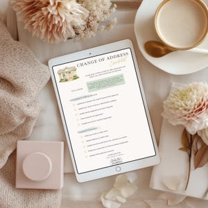 May include: A digital tablet displaying a "Change of Address Checklist" with a house illustration. The checklist includes sections for government records and financial updates. The image is styled with flowers, a cup of coffee, and a decorative block.