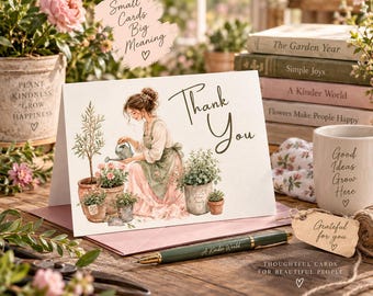 May include: A white greeting card featuring a watercolor illustration of a person in an apron watering potted plants. The text Thank You is printed in dark brown script. The card is displayed with a green pen and a small brown gift tag.