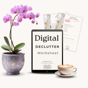 May include: A digital declutter worksheet displayed on a tablet, with the title "Digital Declutter Worksheet". A potted orchid with pink flowers and a cup of coffee with latte art are also present. Several printed worksheets are visible.