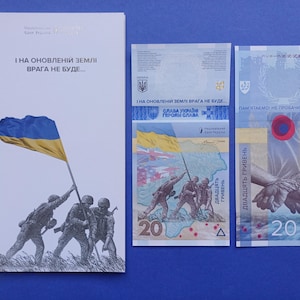 Op de afbeelding: Een verzameling Oekraïense bankbiljetten en een herdenkingskaart. De kaart toont een blauw-gele vlag met soldaten. De bankbiljetten tonen afbeeldingen van soldaten, handen en het getal 20. De tekst op de kaart luidt "I on obnovleniy zemli vraga ne bude..."