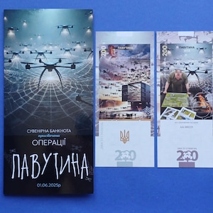 Op de afbeelding: Een verzameling Oekraïense souvenirbiljetten met drone-afbeeldingen. De hoofdbiljet heeft een donkere achtergrond met drones en de tekst "Operatie Web". Twee kleinere biljetten tonen vergelijkbare drone-scènes.