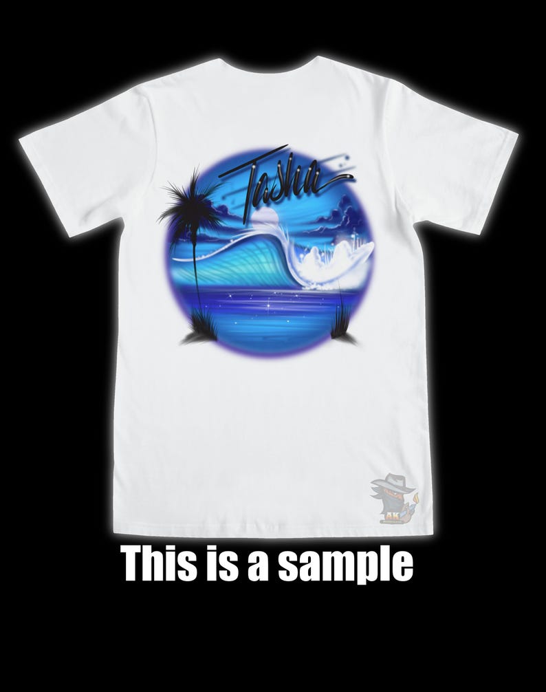 以下が含まれることがあります： 白いTシャツ。青と白の海の波のデザインとヤシの木のシルエットが特徴です。「Tasha」の文字が波の上に書かれています。「This is a sample」の文字がTシャツの下部に印刷されています。