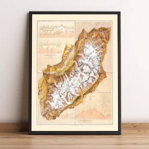 May include: Framed vintage map print of a mountainous region, with detailed topographical information. The map uses a beige, brown, and white colour palette, with a black frame. The print is displayed on a wooden surface.