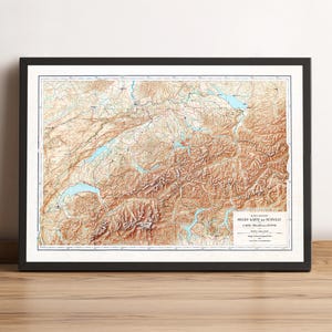 May include: Framed topographic map of Switzerland, featuring a detailed relief with shades of brown and tan, depicting mountains, valleys, and lakes. The map is enclosed in a black frame, suitable for home or office decor.