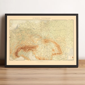 May include: Framed vintage map of Central Europe, featuring detailed geographical information. The map is in shades of beige, brown, and tan, with the title "EUROPE CENTRALE" at the top. The map is encased in a black frame.