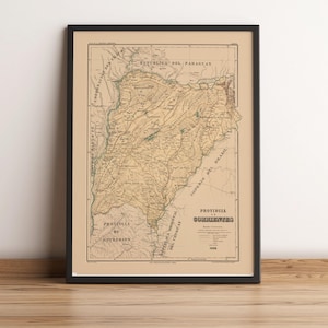 May include: Framed vintage map of a region, featuring detailed geographical information. The map is in sepia tones, with text in Spanish. The frame is black, and the map is displayed on a wooden surface.