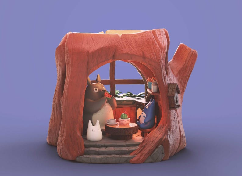 Op de afbeelding: Een grillig diorama met personages uit de animatiefilm "My Neighbor Totoro". De sc&egrave;ne speelt zich af in een boomstam, met Totoro die watermeloen eet. Andere personages zijn aanwezig, samen met een kleine tafel en een cactus.