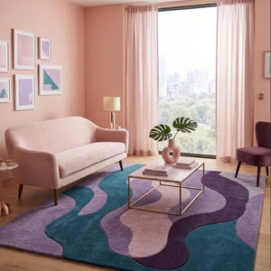 May include: A living room with a pink color scheme. A pink sofa, curtains, and walls create a cohesive look. A colorful rug with blue, purple, and pink wave patterns sits on the floor. A square coffee table with a gold frame and a vase with plants are in the center.