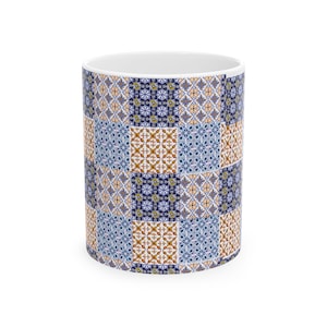 Peut inclure: Un mug cylindrique en céramique orné d'un motif patchwork répétitif de carreaux carrés. Le design se compose de motifs géométriques et floraux alternés en bleu, blanc et orange disposés en grille, avec un intérieur et un bord blancs.