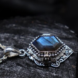 May include: A silver pendant necklace featuring a faceted, blue-green gemstone. The gemstone is set in an ornate, detailed silver setting with decorative elements. The necklace chain is also silver.