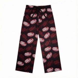 May include: A white ceramic mug with a black handle and the text "But First, Coffee" in a bold, black font. The mug is set against a blurred background, suggesting a cozy setting.