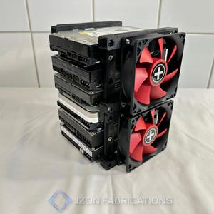 May include: A stack of five hard drives secured in a black 3D-printed frame with two cooling fans attached to the front. The fans feature black frames and red blades with a white plus sign logo in the center. The text JZON FABRICATIONS is visible.