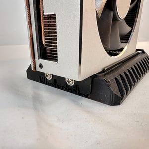 K&ouml;nnte beinhalten: Eine silberne und schwarze Computer-Grafikkarte mit einem L&uuml;fter. Die Karte hat eine schwarze Basis mit einem geriffelten Design. Der L&uuml;fter ist schwarz und silber, und die Karte hat Kupferk&uuml;hlk&ouml;rper.