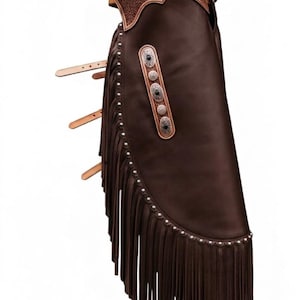 May include: Brown leather chaps with silver studs and fringe. The chaps have a textured leather upper section and decorative silver conchos. Adjustable leather straps are visible.