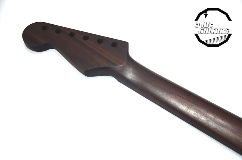 May include: A dark brown guitar neck with six tuning peg holes. The neck is made of wood and has a smooth finish. The headstock is shaped in a classic design. The logo "3 Hit Guitars" is in the upper right corner.